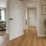 Puerta de interior abierta junto a suelo laminado recién instalado, con una planta decorativa